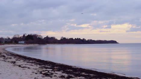 static view of the baltic sea meeting an empty, curved beach at lapmezciems in latvia with sunset reflecting on the water