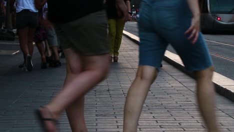 legs of people walking on avenue jean medecin in nice, southern france. no faces. guy on skateboard passes by camera. tram on the road in the background.
