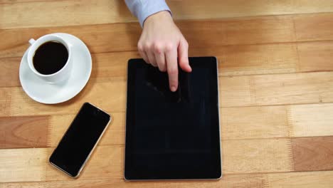 Businesswoman-using-digital-tablet-at-desk-with-cup-of-coffee-and-mobile-phone-on-table