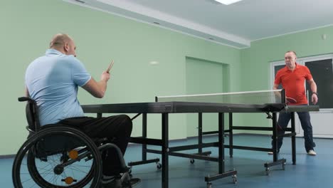 a man in a wheelchair plays ping pong. people with disabilities play table tennis. rehabilitation of the disabled. sport.