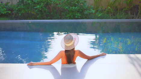 a woman in a swimming pool stretches her arm out along the end of the pool