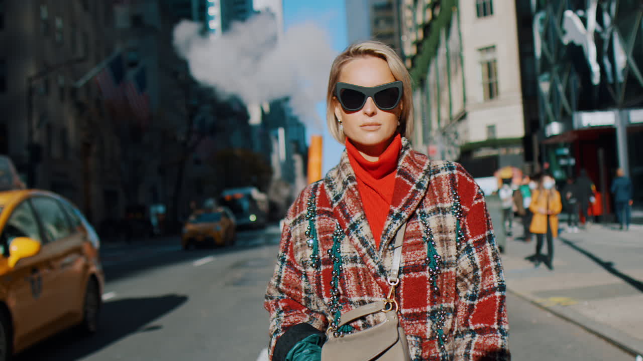 New York, USA, 5 October 2025: Fashionable woman walking on New York City street with taxi. Front view of woman in red turtleneck and plaid coat standing on Manhattan street with yellow cab