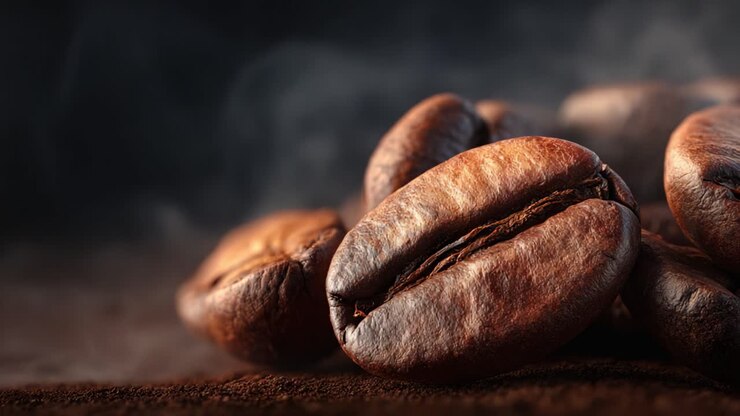 Primo piano di chicchi di caffè appena tostati che sprigionano aroma, catturando l'essenza del sapore e della ricchezza in un ambiente splendidamente scuro e caldo.