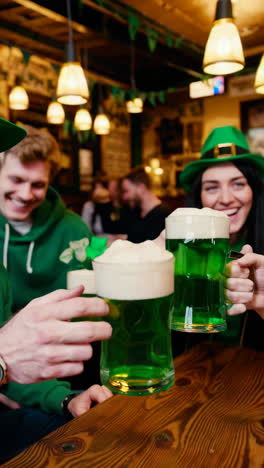 friends celebrating st. patrick's day with green beer at a pub