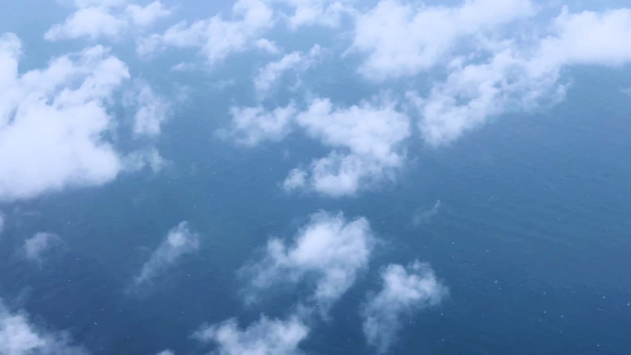 Fluffy white clouds floating over the ocean seen from an aerial view on a calm day