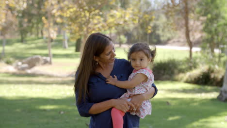 Mixed-race-Asian-mum-with-toddler-in-park-walks-in-to-focus