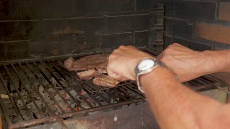 manos cortando con cuchillo y tenedor carne en barbacoa.