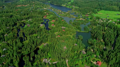 Aerial-drone-backward-moving-shot-over-ponds-and-houses-surrounded-by-dense-vegetation-on-a-sunny-day