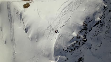 bottom up drone shot of a snowboarder on a snowy mountain top in switzerland