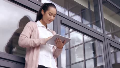 아시아 사업가 여자가 밖에서 태블릿을 사용하고 있습니다.