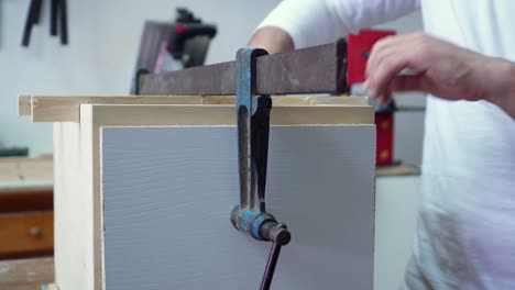 Close-up-on-skilled-carpenter-busy-at-work-assembling-a-wooden-crate-in-workshop