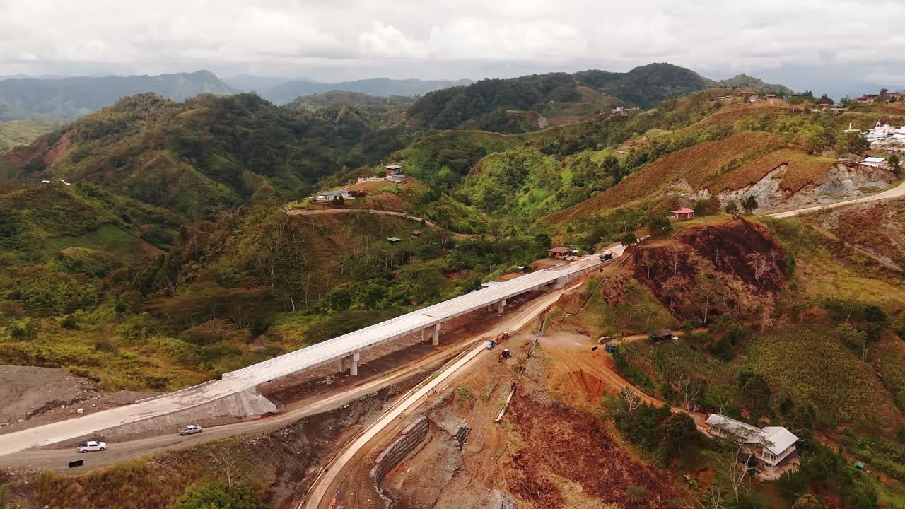 Stunning drone shot of a bridge under construction winding through lush mountain terrain—perfect for infrastructure, development, and cinematic nature projects