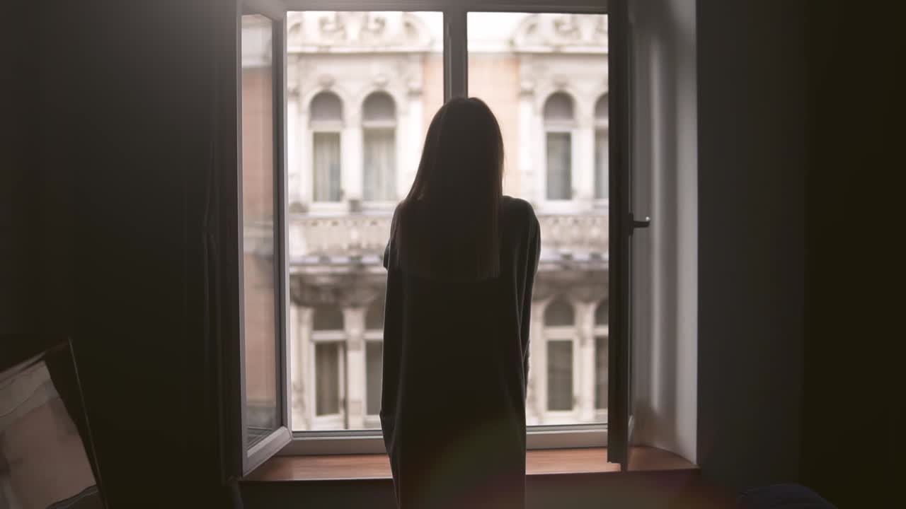 금발 소녀는 아침에 집에서 창문 근처에 격자 무늬나 깔개로 몸을 가렸습니다.