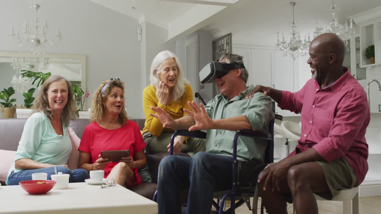 Video of happy senior man in wheelchair using vr headset and having fun with diverse friends
