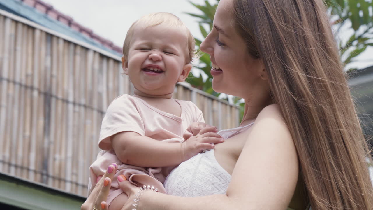 행복한 엄마가 밖에서 아기 소녀를 안고 있습니다.