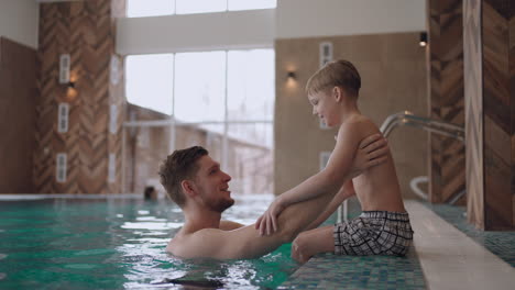 Familien-Wellnesscenter-Vater-Und-Kleiner-Sohn-Schwimmen-Und-Spielen-Im-Pool-Glücklicher-Junge-Mit-Papa