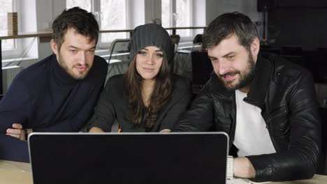 team of young professionals watching a video in a creative office. business discussion. coffee cups on the table. shot in 4k