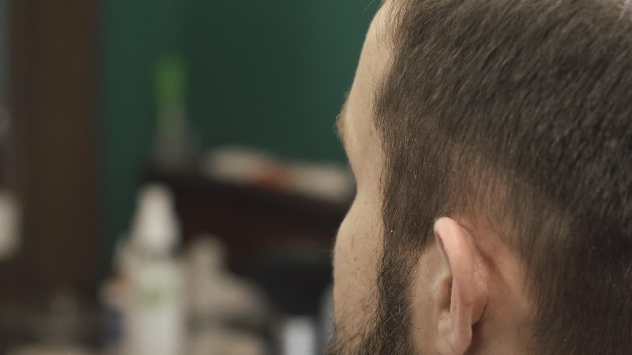 Close-up of a barber cutting a man's hair with electric clippers