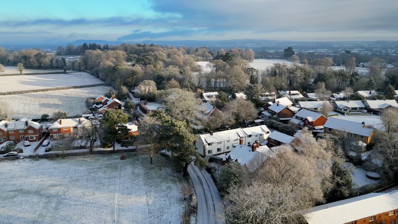 A tranquil winter morning in a small English village, with soft sunlight highlighting the snow-dusted cottages.