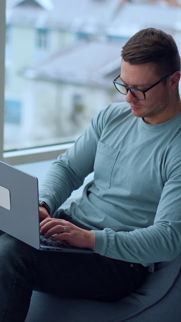 Man working on laptop at home near a window