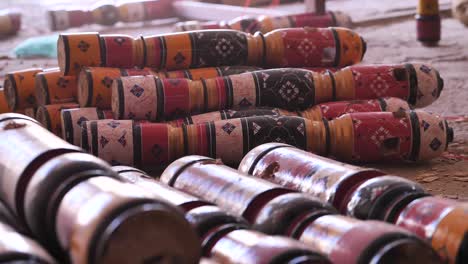 piles of wooden colourful charpai traditional leg posts resting on workshop floor