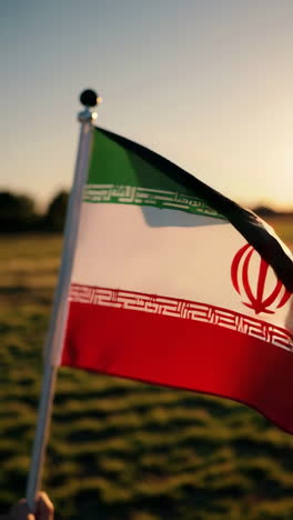 iranian flag waving in a field at sunset