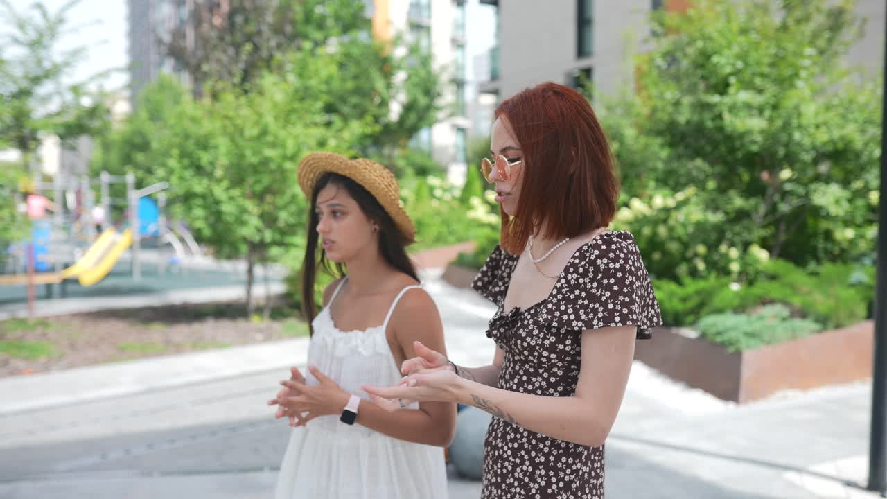 두 소녀 가 도시 공원 에서 야외 에서 대화 하고 있다