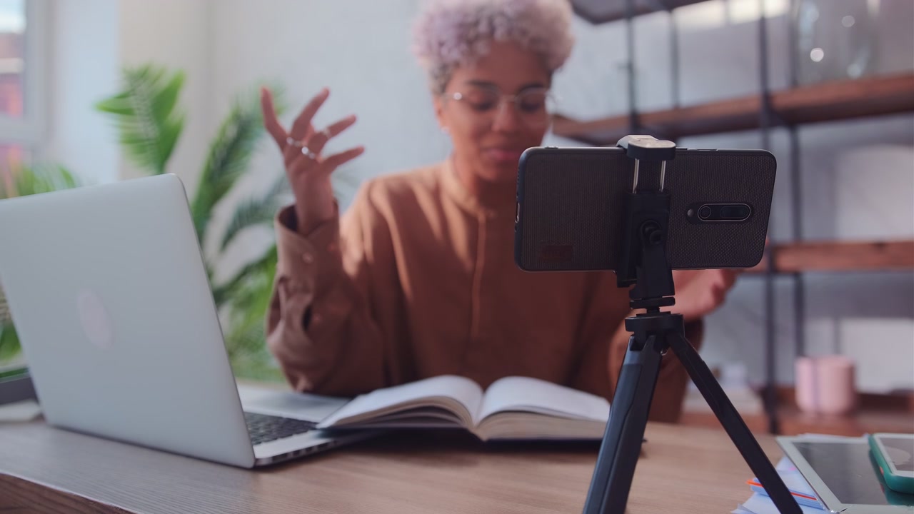 Młoda, radosna blogerka afroamerykańska prowadzi wideopodcast na telefonie.