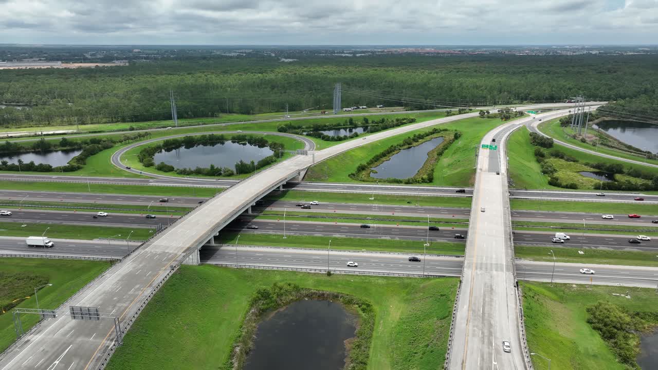 Aerial view of Florida highway interchange with lush greenery and ponds. Captures busy traffic flow and modern infrastructure. Ideal for transportation and urban planning themes. aerial wide shot.
