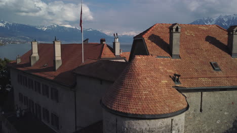 Aerial-rise-and-fly-over-of-a-renaissance-building-along-the-Lake-Geneva-shoreline-near-Rivaz,-Switzerland