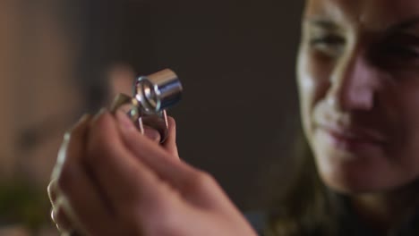 Close-up-of-caucasian-female-jeweller-checking-quality-of-jewelry-in-workshop