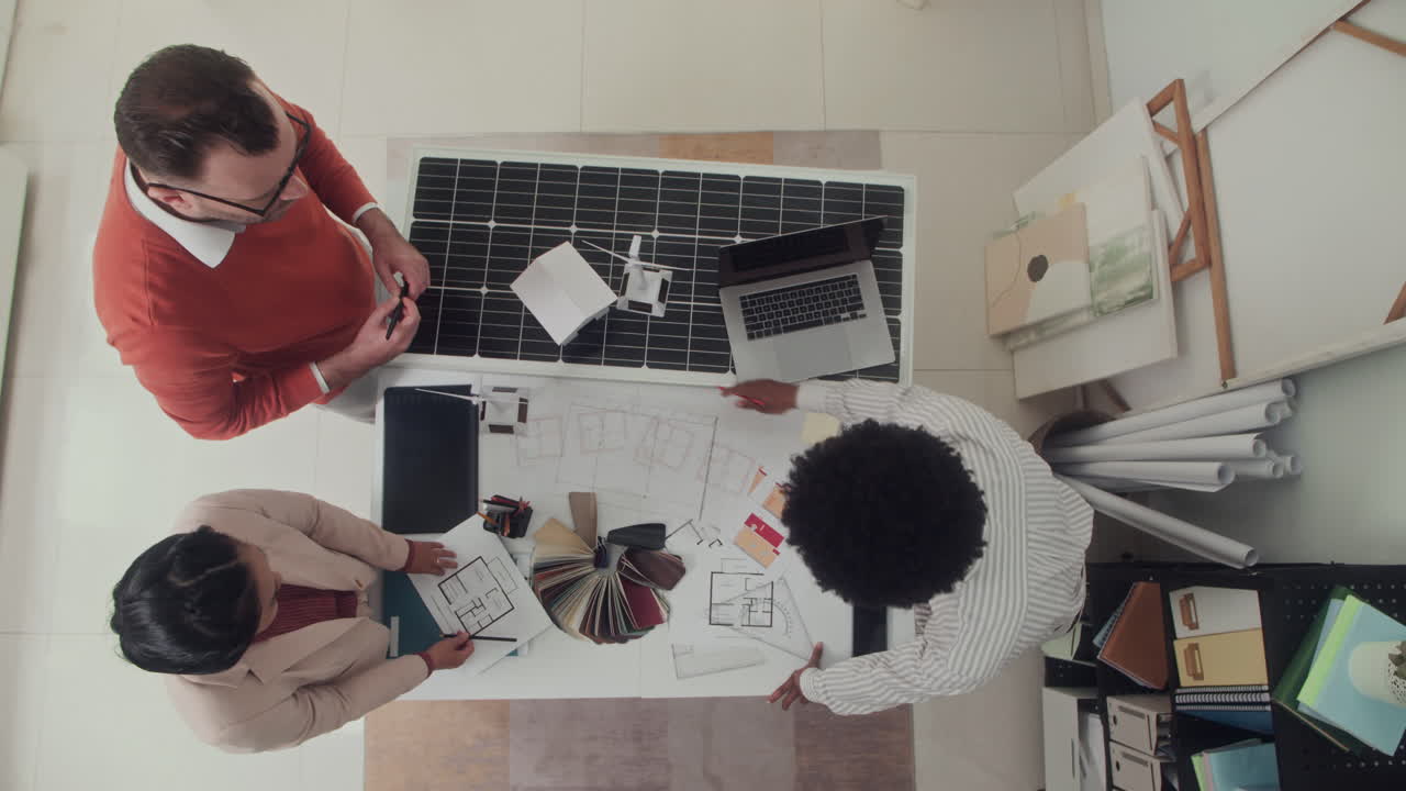 Multiethnic Engineers Working on Solar Power Project at Table