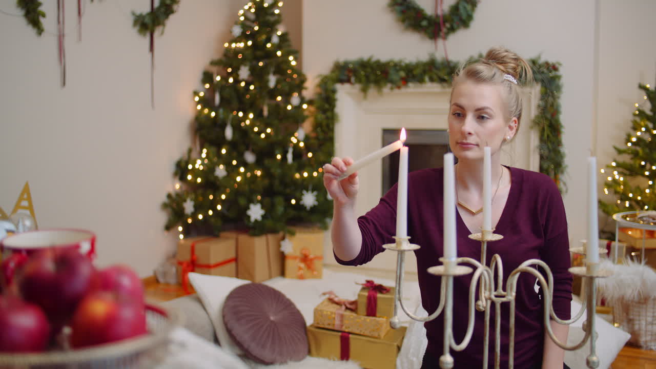 женщина зажигает свечи в гостиной дома