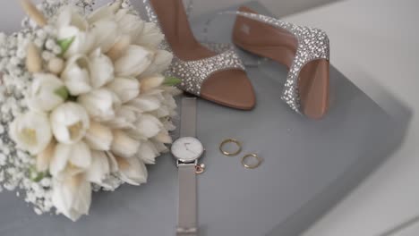 elegant bridal bouquet rings heels and watch arranged on soft surface