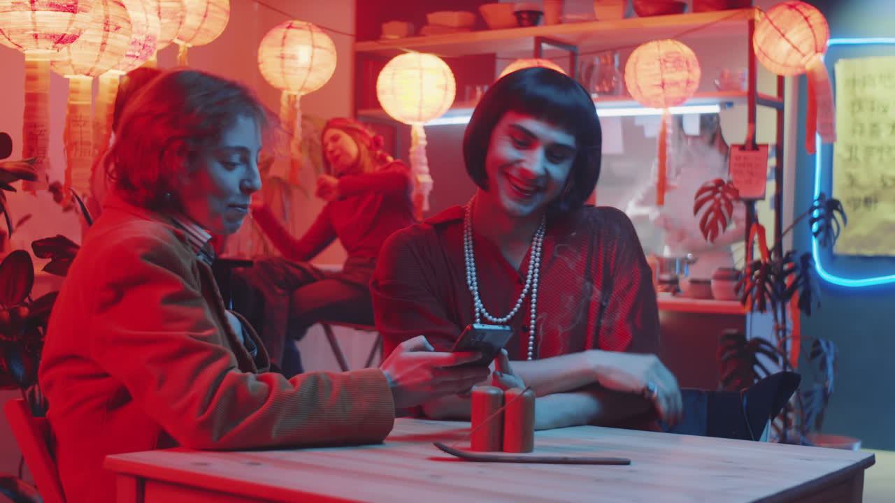 즐거운 트랜스젠더 남자와 여자친구가 채팅하고 스마트폰을 사용하고 있습니다.