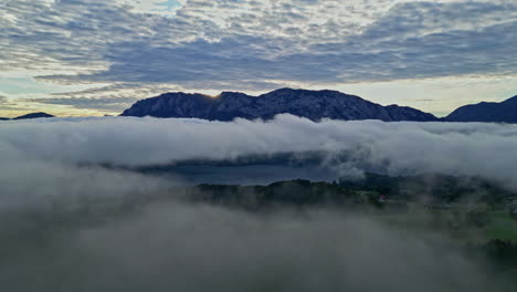 Aerial-view-of-fog-moving-over-the-green-nature-in-Austria-during-sunset