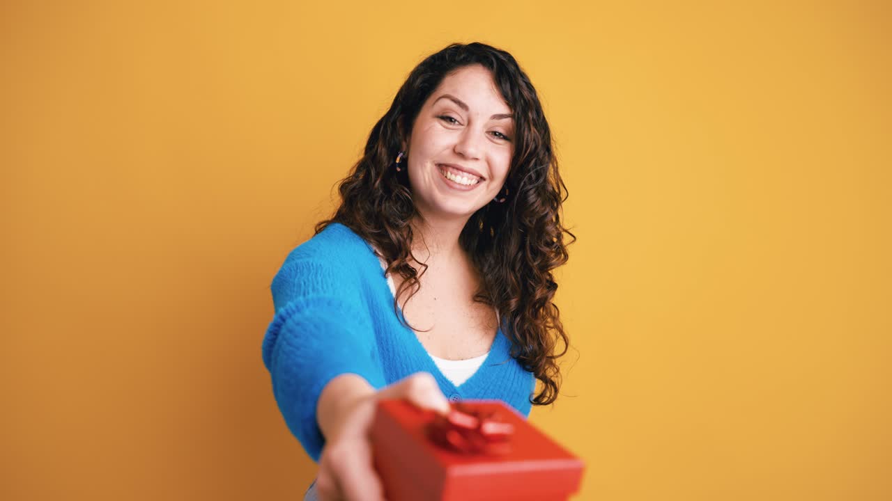 Donna felice che offre una scatola regalo rossa verso la fotocamera