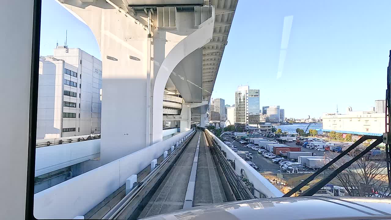 A monorail glides through Tokyo's cityscape, capturing urban architecture and vibrant skies in bright daylight