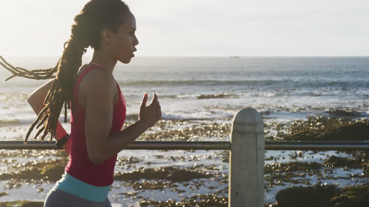 mujer afroamericana en ropa deportiva corriendo en el paseo marítimo por el mar
