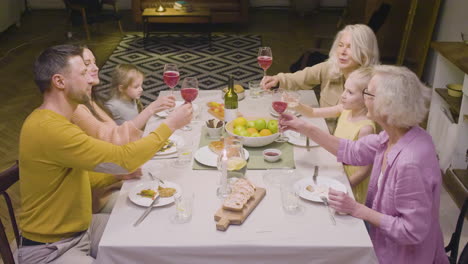 top view of a family toasting during a dinner sitting at a table and enjoying a great time