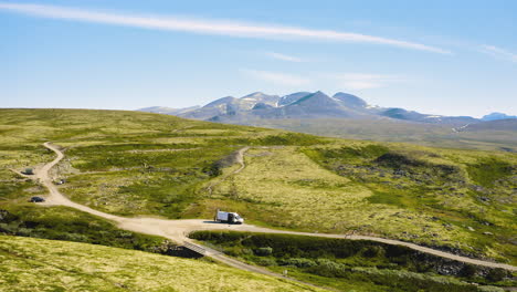 white campervan parked by the road with natural green mountain landscape in rondane national park in norway