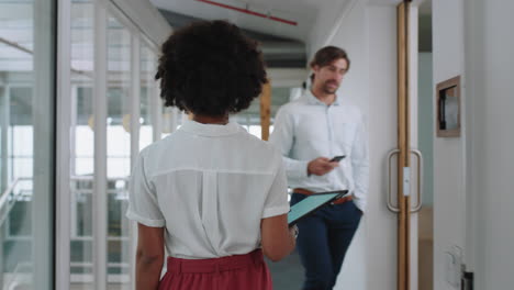 vista trasera mujer de negocios de raza mixta caminando por la oficina sosteniendo una computadora tablet carrera exitosa en el lugar de trabajo corporativo 4k