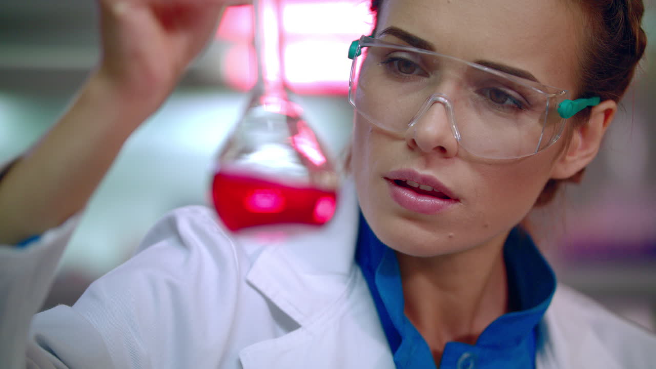 mujer química en el laboratorio. mujer química analizando líquido químico en un frasco de laboratorio