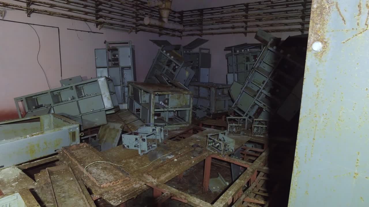 Interior Of Abandoned Control Room With Broken Electrical Cabinets And Equipment In Chernobyl Exclusion Zone, Ukraine. panning shot
