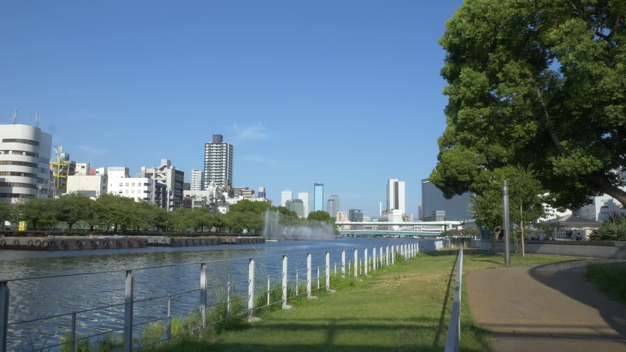 City Buildings And River Fantasy Fountain Show Seen From Nakanoshima Park In Osaka, Japan. - wide shot
