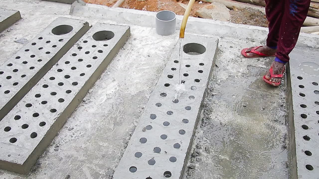 Indian mason worker pouring water over concrete slab to ensure thorough hardening of the surface
