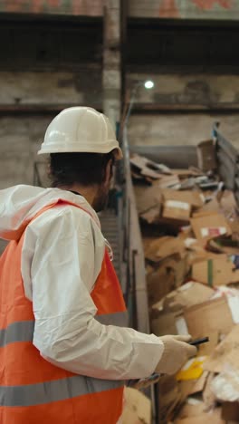 recycling plant worker inspecting waste