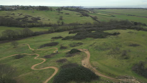 ciclista de montaña montando a lo largo de un sinuoso sendero cuesta abajo en hadleigh park, drone