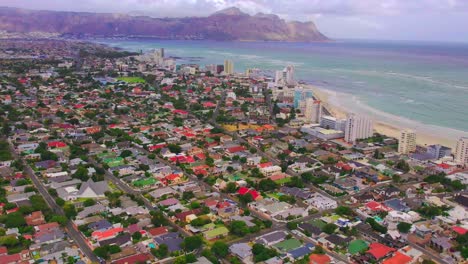 Establecer-Toma-Aérea-De-La-Ciudad-Del-Cabo,-Cámara-Aérea-De-Drones-Avanzando-Colorido-Barrio-A-La-Playa-De-La-Ciudad-Del-Cabo,-Hermoso-Paisaje,-Vista-Aérea-Del-Paisaje-Urbano