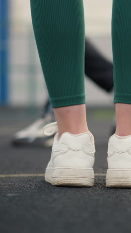 leg view of three athletes in joggers and sneakers walking on court with a blurred background, another athlete's leg is visible in joggers and sneakers, walking in the same direction